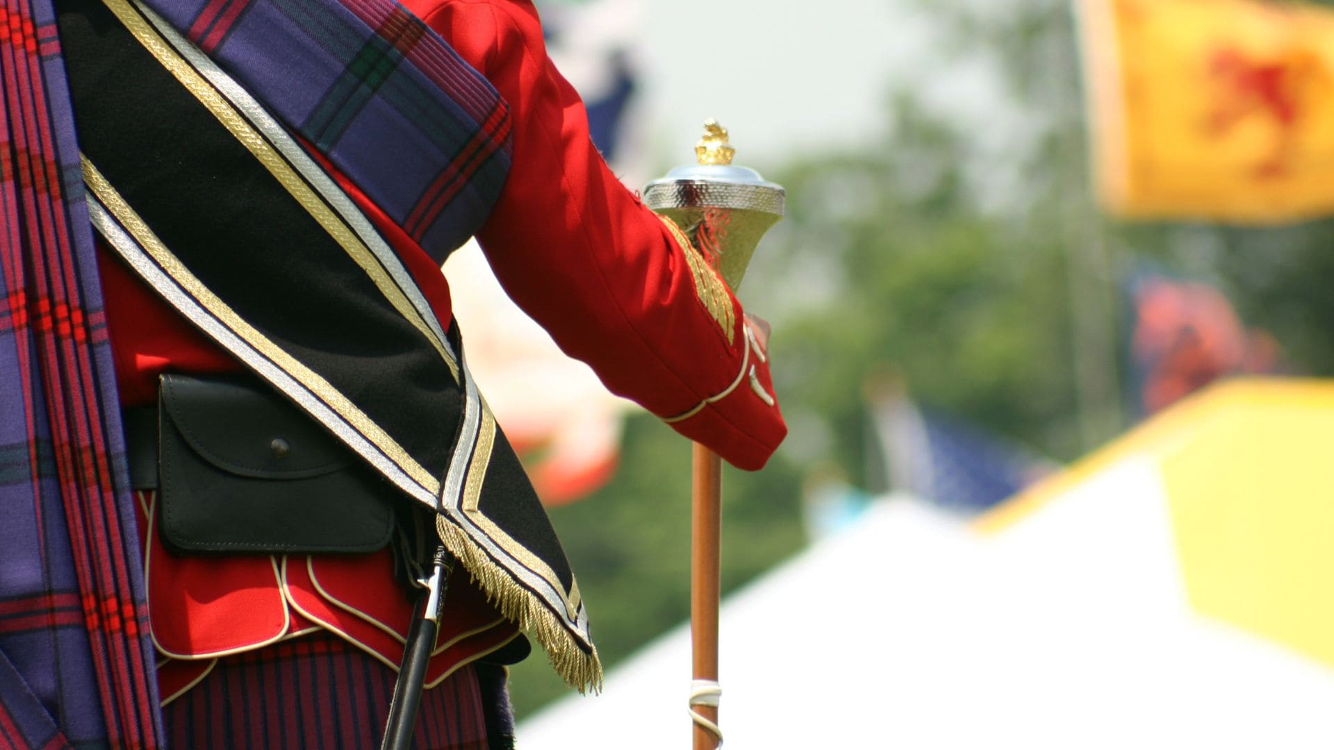 A Scottish drum Major standing at attention, holding his mace.